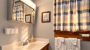 Un baño con lavamanos, espejo, toallero y cortina de ducha.