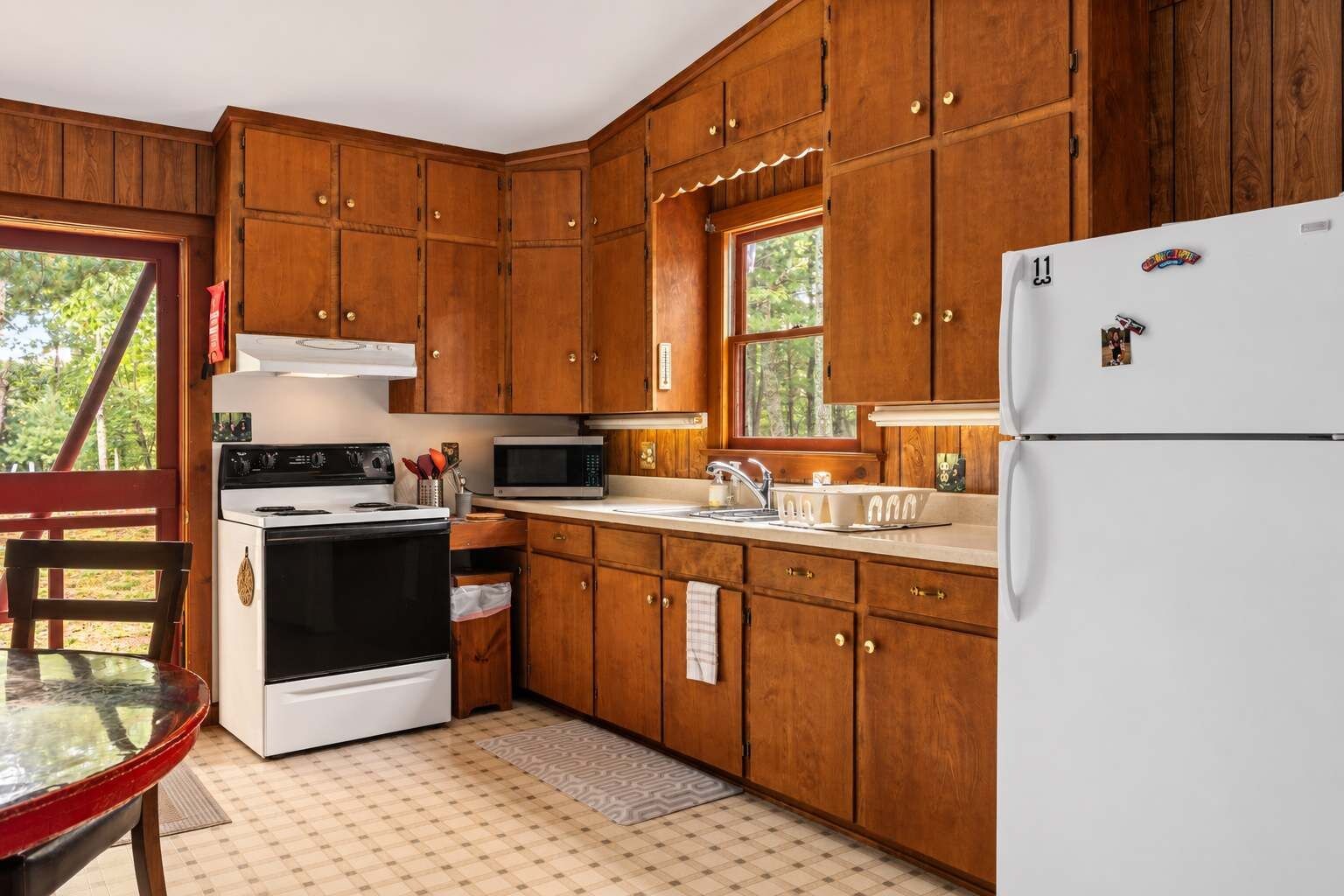Une cuisine avec des meubles de rangement en bois, un réfrigérateur blanc, une cuisinière et un four à micro-ondes.
