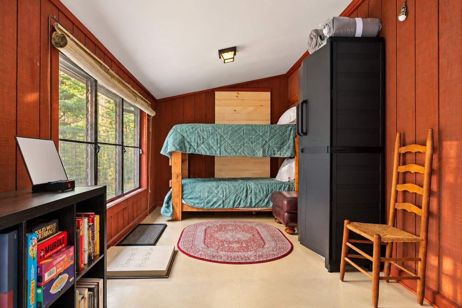 Ein kleines Zimmer mit einem Etagenbett, einem Schreibtisch mit Computer, einem Bücherregal und einem Kühlschrank.