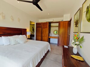 A hotel room with a bed, a desk, a vanity, and a bathroom visible through an open door. - Chic Coastal Sanctuary 1-BR condo steps from the beach w/Private Terrace (Santa Cruz Huatulco)