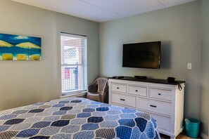 A bedroom with a bed, a dresser, a television, and a window with blinds. - Beachview Condos #103 - Popular Family Retreat Just 30 Seconds from the Sand (South Padre Island)