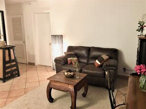 A living room with a leather sofa, a wooden coffee table, and a lamp. - 1-Bedroom Apartment in Pelican Key with Shared Pool & Private Parking (Koolbaai)