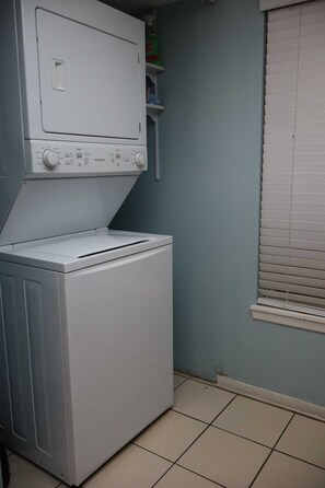A compact laundry area with a front-loading washing machine and a dryer. - Beachview Condos #105 - "One of a Kind" Family Retreat Steps from the Gulf (South Padre Island)