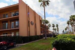 Een meerhoog hotel met balkons, palmbomen en een golftrolley.