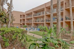 Een hotel met meerdere verdiepingen, voorzien van balkons, een binnentuin met zitplaatsen en tropische beplanting.