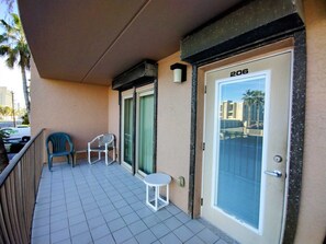A balcony with a door labeled '206,' a small table, and two chairs. - Beachview Condos #206 - Popular 2-BR Retreat with Pure Water & Netflix (South Padre Island)