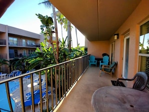 A balcony with a pool, chairs, and a view of a building with balconies. - Beachview Condos #208 - Spacious 2-BR Retreat Just 30 Seconds from the Beach (South Padre Island)