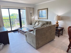 A living room with a sofa, a glass coffee table, a lamp, and a view of the outdoors through a sliding door. - Continental #101 - Ground-Floor Beachfront Luxury Steps from the Gulf (South Padre Island)