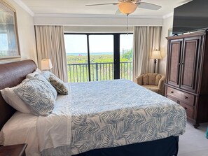 Una camera d'albergo con un letto grande, un armadio, una sedia e un balcone con vista.