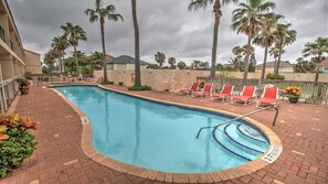 A swimming pool with red lounge chairs, palm trees, and a brick walkway. - Dolphin #23 - Spacious Families-Only Retreat Across from the Beach (South Padre Island)