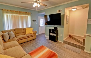 A living room with a sofa, a television, and a staircase. - Dolphin #23 - Spacious Families-Only Retreat Across from the Beach (South Padre Island)