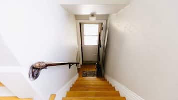 Eine Holztreppe mit weißen Wänden und einer Tür am oberen Ende.