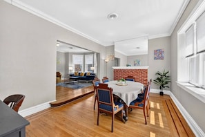 A dining area with a brick accent wall, wooden flooring, and a round table with chairs.