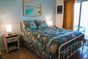 A bedroom with a bed, two bedside tables, a nightstand, a window with curtains, and a wall-mounted picture. - Dolphin 28 - Spacious Families-Only Retreat Across from the Beach (South Padre Island)