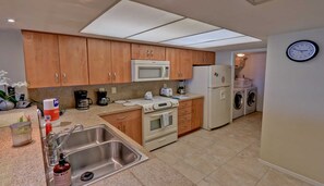 A compact kitchen with a microwave, oven, sink, and a washing machine. - Premier 3-BR Family Escape at Edgewater #507 - Spectacular Corner Gulf Views (South Padre Island)