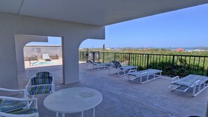 Un espacio al aire libre techado con sillones de descanso y una piscina, con vistas a la playa.