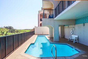 A swimming pool with a metal ladder, a bench, and a chair on a balcony with a view of greenery. - Beachfront Studio at Florence 1 #608 - Incredible Gulf Views & Resort Comfort (South Padre Island)