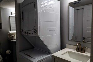 Un baño pequeño con lavadora integrada, un lavabo y un espejo.