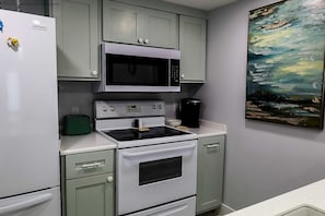 A kitchen with a white refrigerator, a microwave, an oven, and a coffee maker. There is a green appliance on the counter and a painting on the wall. - Gulfpoint #3102 - Spacious 1-BR Family Escape Near Beach Park At Isla Blanca (South Padre Island)
