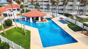 A hotel with a large swimming pool, multiple balconies, and palm trees. - Gulfpoint #3102 - Spacious 1-BR Family Escape Near Beach Park At Isla Blanca (South Padre Island)