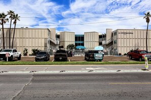Um estacionamento com vários carros, um edifício com a inscrição 'LA INTERNATIONAL CONDOMINIUM' e um céu claro.