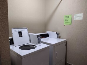 A laundry room with a front-loading washer and dryer, a control panel, and a note on the wall advising not to wash sandy clothes. - Landfall Towers #71 - Breathtaking Bayfront Living with Boat Slip Access (South Padre Island)