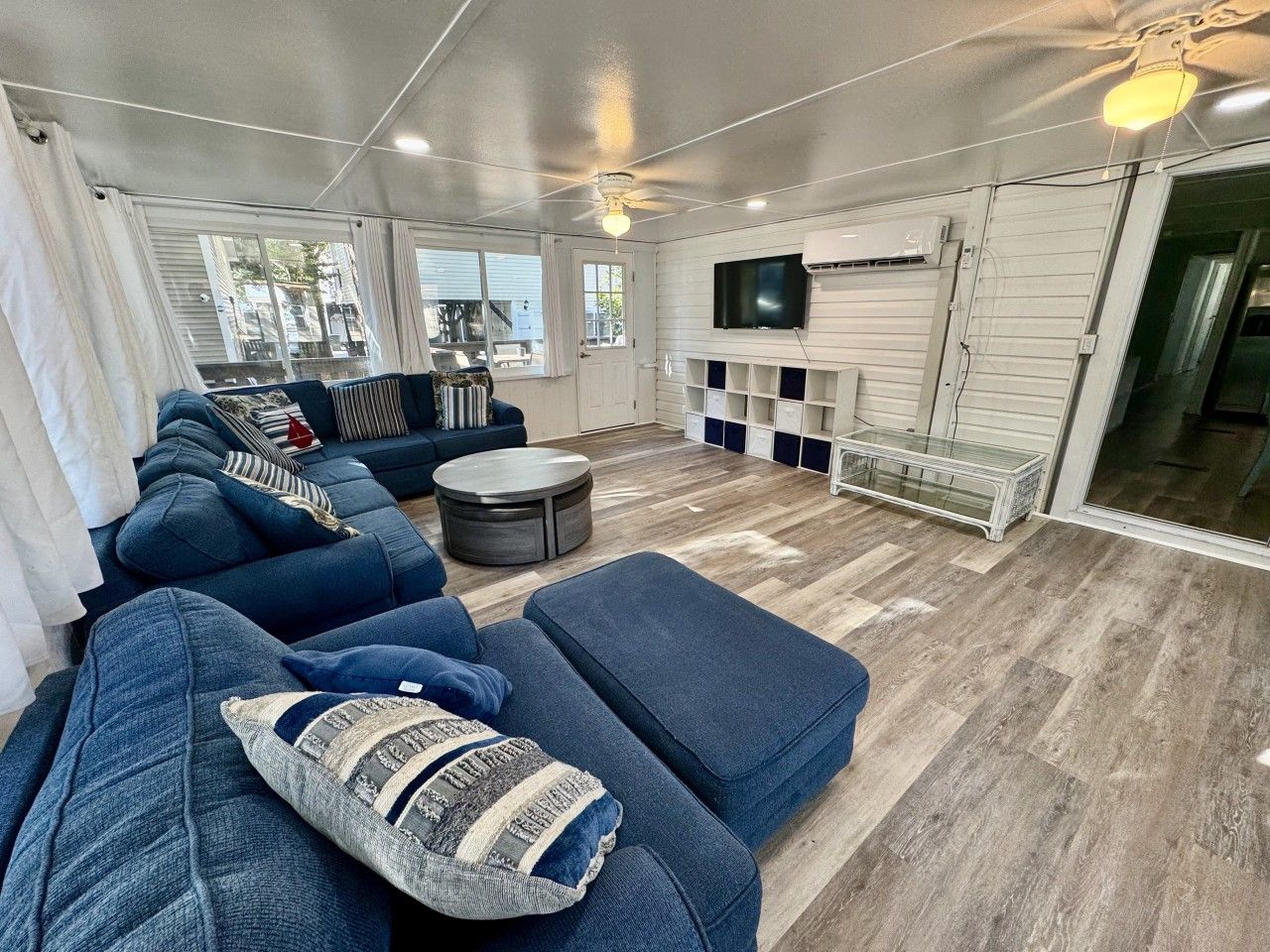 A living room with a sectional sofa, a round coffee table, and a television mounted on the wall.