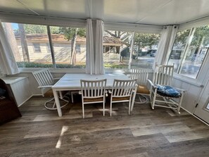A covered patio area with a dining table and chairs, large windows, and a view of the outside. - Pet-Friendly Ocean Lakes 4BR | Limo Golf Cart | Sleeps 9 (Myrtle Beach)