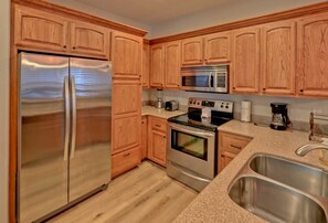 Eine Küche mit Holzschränken, Edelstahlgeräten, einer Spüle mit zwei Becken und einer Arbeitsplatte aus Granit.