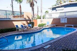 Piscina com espreguiçadeiras e área cercada.