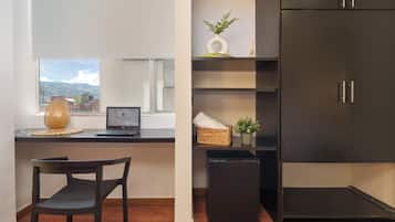 Ein modernes Zimmer mit Schreibtisch, Laptop, Stuhl und einem dunklen Schrank.