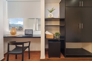 Een moderne kamer met een bureau, laptop, stoel en een donkere kast.