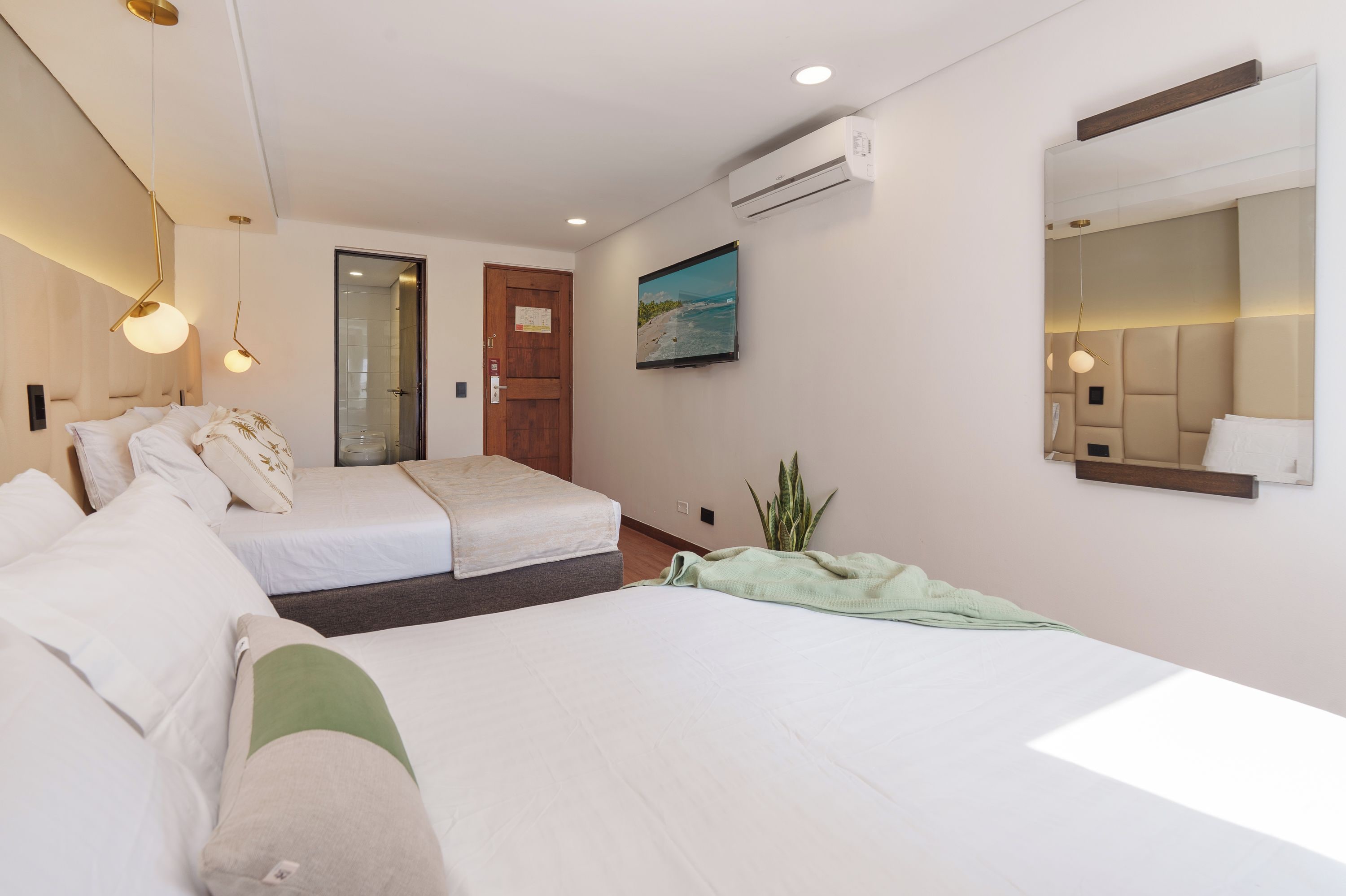 Une chambre d’hôtel avec deux lits, un grand miroir, un appareil de climatisation et un tableau au mur.
