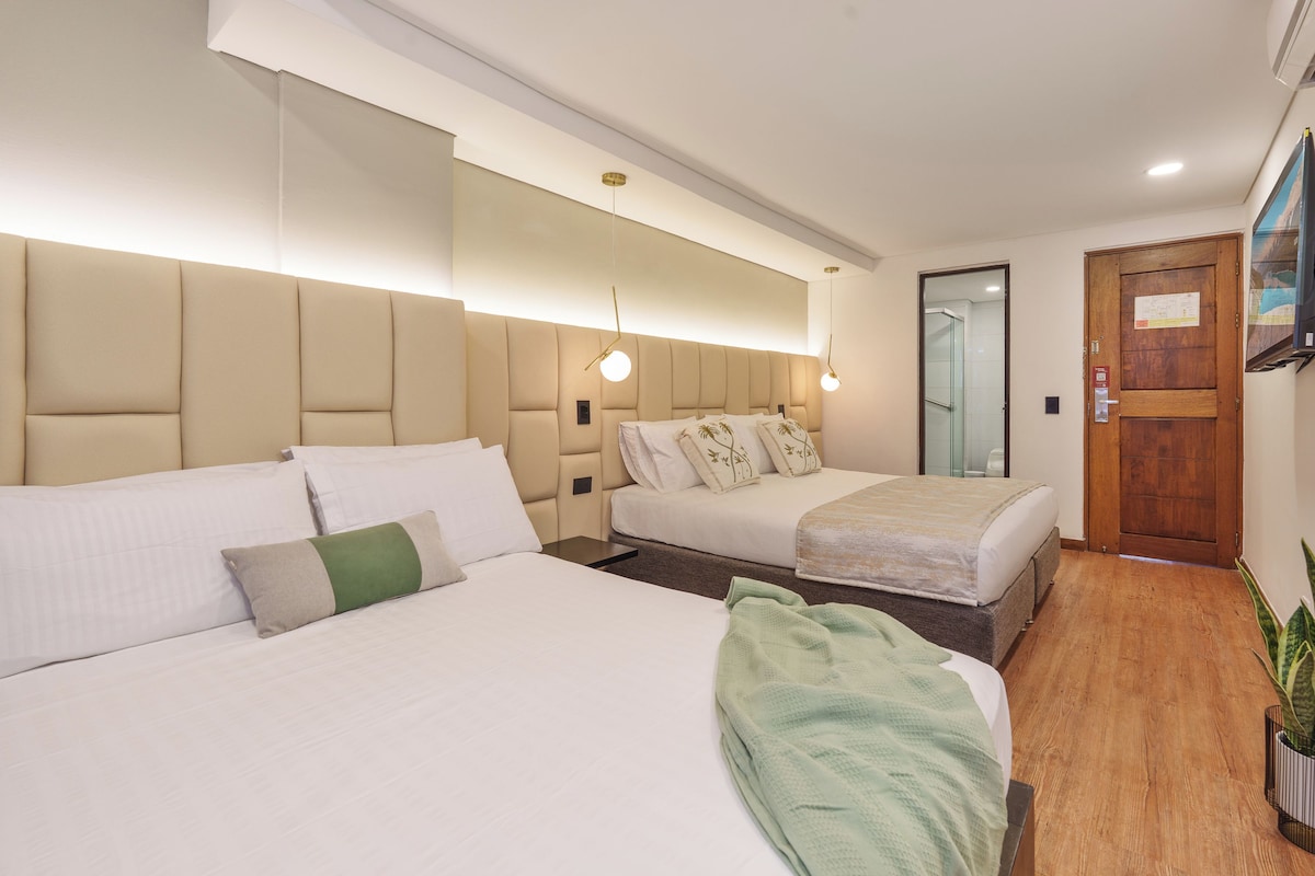 Habitación de hotel con dos camas, piso de madera, una puerta y un espejo.