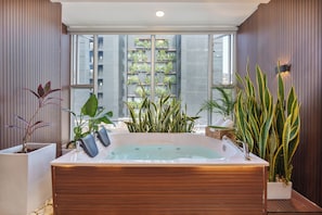 A modern bathroom with a large bathtub, wooden paneling, and potted plants. - Veranova hotel (Medellín)