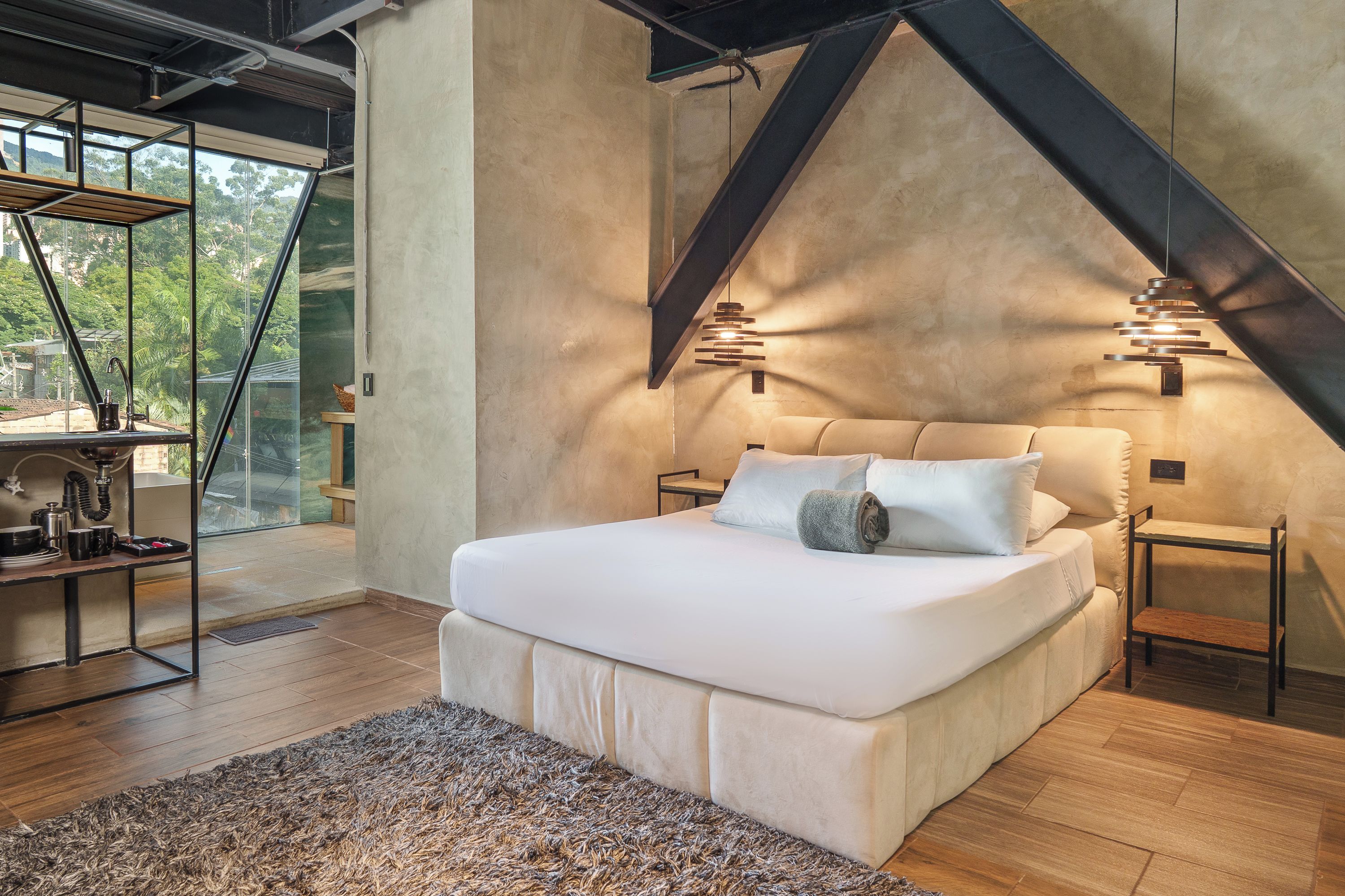 Ein modernes Schlafzimmer mit einem großen Bett, Holzböden und Blick durch eine Glastür.