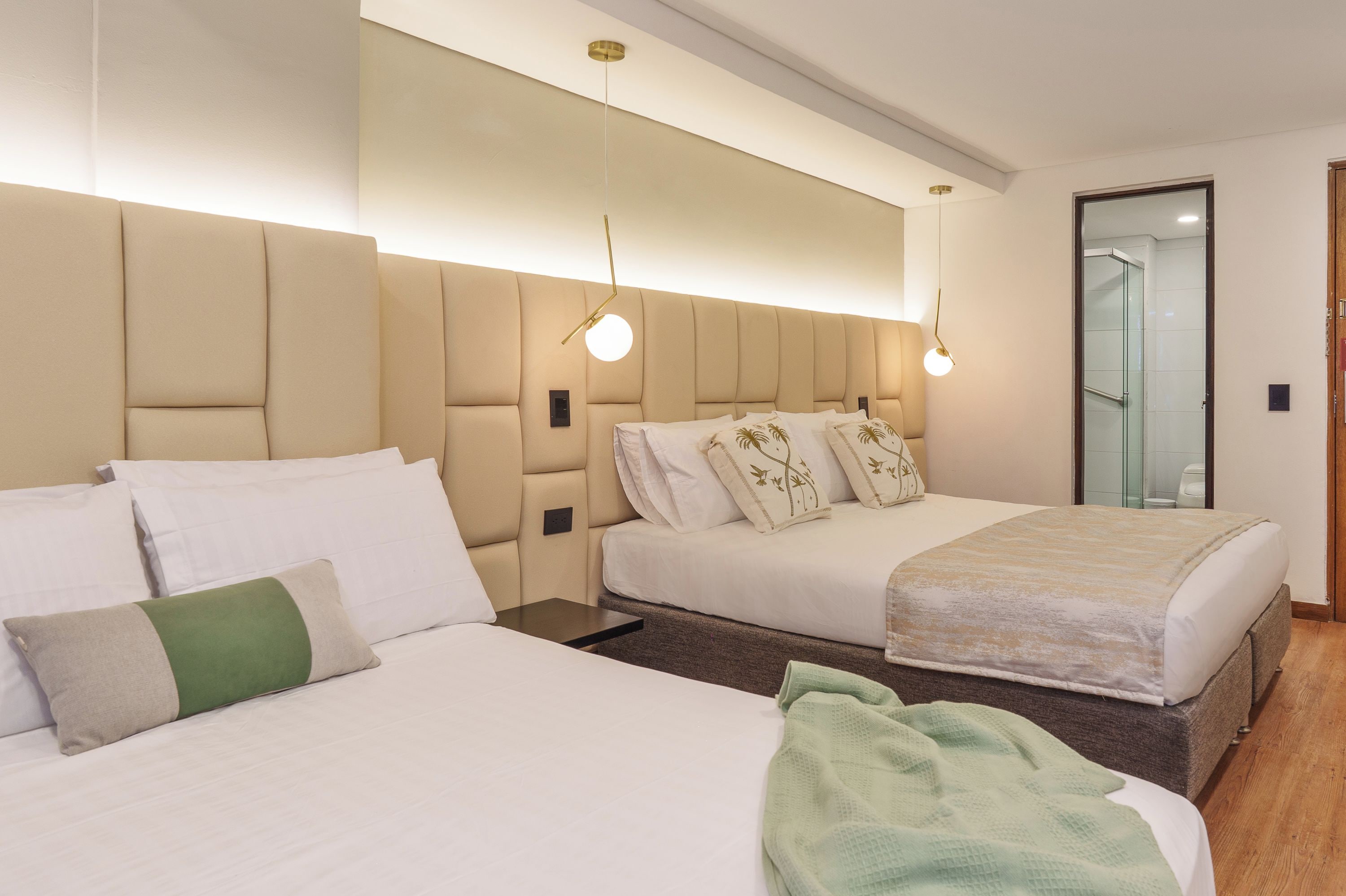 Ein Hotelzimmer mit zwei Betten, einem großen Spiegel und einer modernen Deckenleuchte.