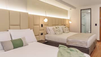 Une chambre d’hôtel avec deux lits, un grand miroir et un luminaire moderne au plafond.