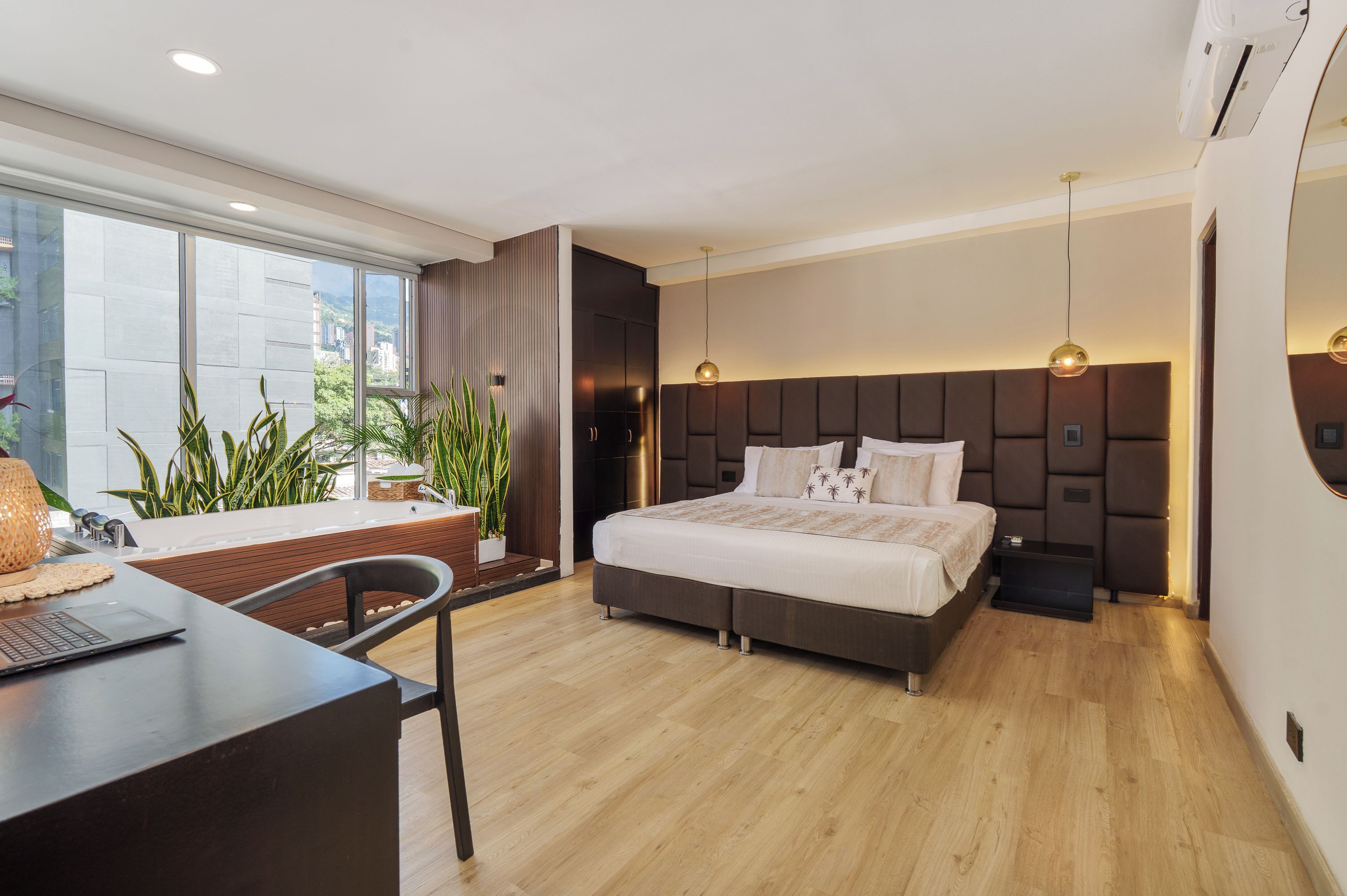 Ein modernes Schlafzimmer mit einem großen Bett, einem Schreibtisch und Blick auf die Stadt.
