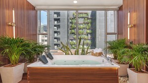 Área de spa com hidromassagem, plantas em vasos e vista para um edifício com sacadas.
