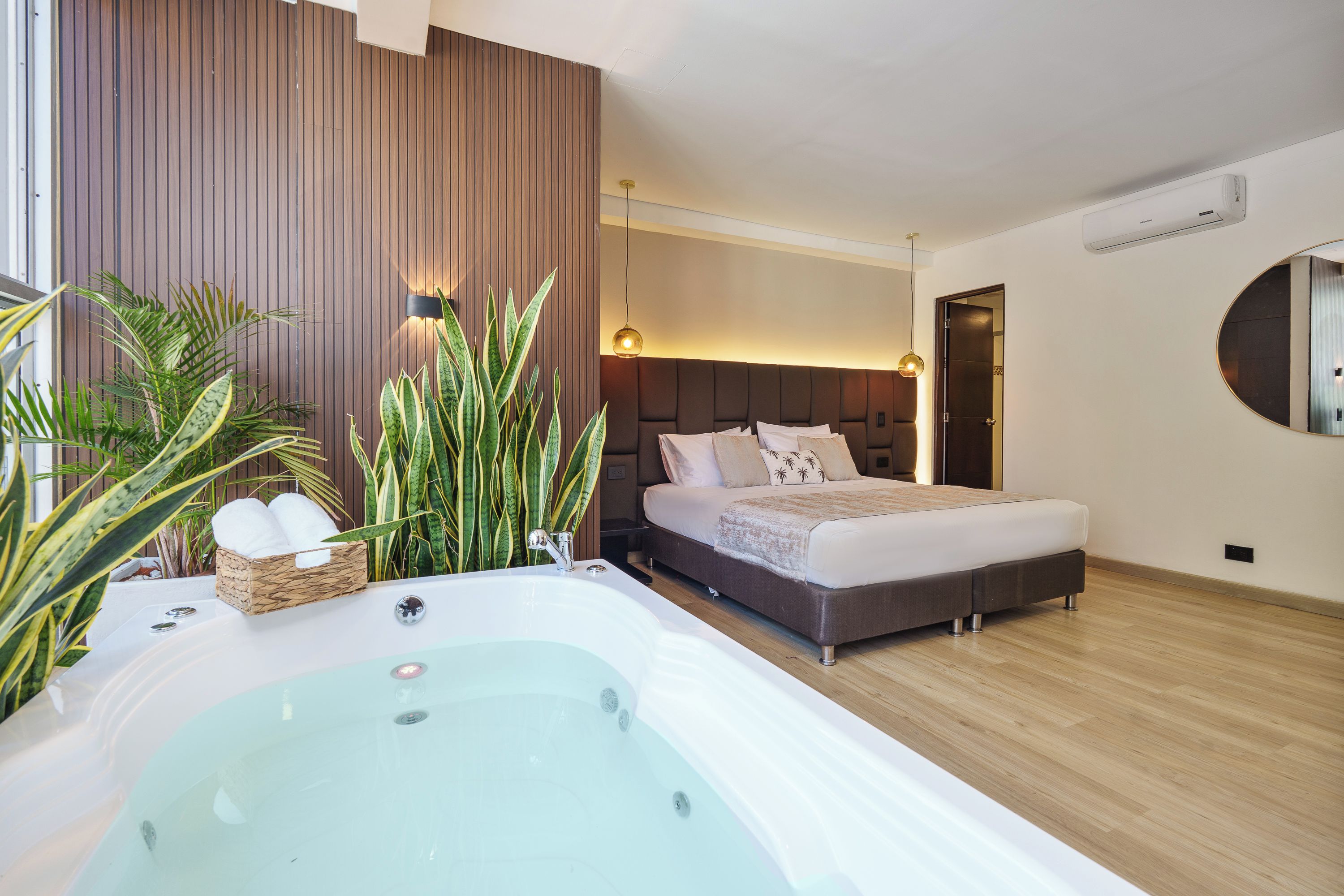 Ein modernes Schlafzimmer mit einem großen Bett, einer integrierten Badewanne und einer Holzwandverkleidung.