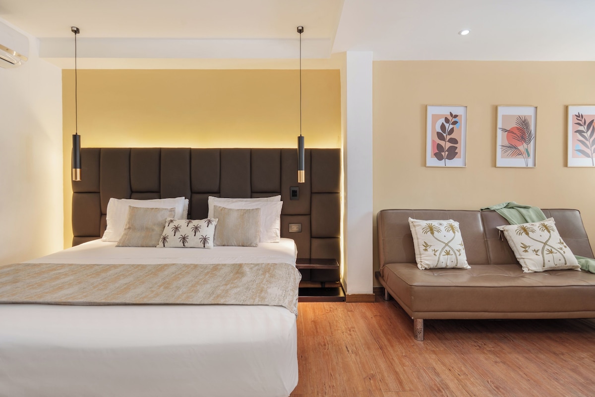 Una habitación de hotel con una cama grande, un sofá y obras de arte en las paredes.