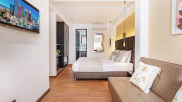 A hotel room with a bed, a sofa, a TV, and a cityscape view.