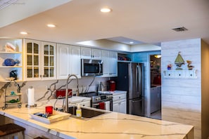 A modern kitchen with white cabinets, stainless steel appliances, and a marble countertop. - Seville #602 - Premier Top-Floor Beachfront Living with Panoramic Gulf Views (South Padre Island)