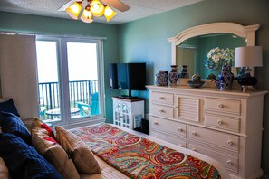 A bedroom with a bed, dresser, television, and a balcony with a chair. - Seville #602 - Premier Top-Floor Beachfront Living with Panoramic Gulf Views (South Padre Island)