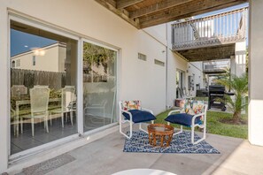 A patio with two chairs, a round table, and a barbecue grill. - Easy-Access Ground Floor Escape at Sun Dancer #5 - Perfect for Families (South Padre Island)