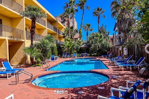 A pool area with multiple swimming pools, lounge chairs, and palm trees. - Ventura #201 - 1/2 Block to the Beach Affordable 1-Bedroom Escape (South Padre Island)