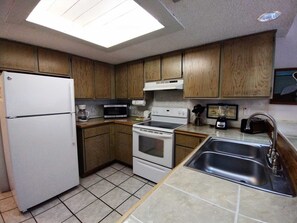 A compact kitchen with a refrigerator, microwave, stove, and sink. - Affordable 2-BR Retreat at Surfside 1 #206 - Just 2 Minutes to the Beach (South Padre Island)