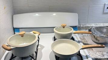 A kitchen with a white stove, three pots, and a strainer on the counter.