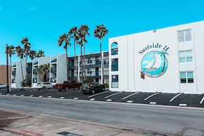 A building with a mural of a sailboat and palm trees, labeled 'Surfside II.' - Affordable 2-BR Escape at Surfside 2 #107 - Steps from the Sand (South Padre Island)